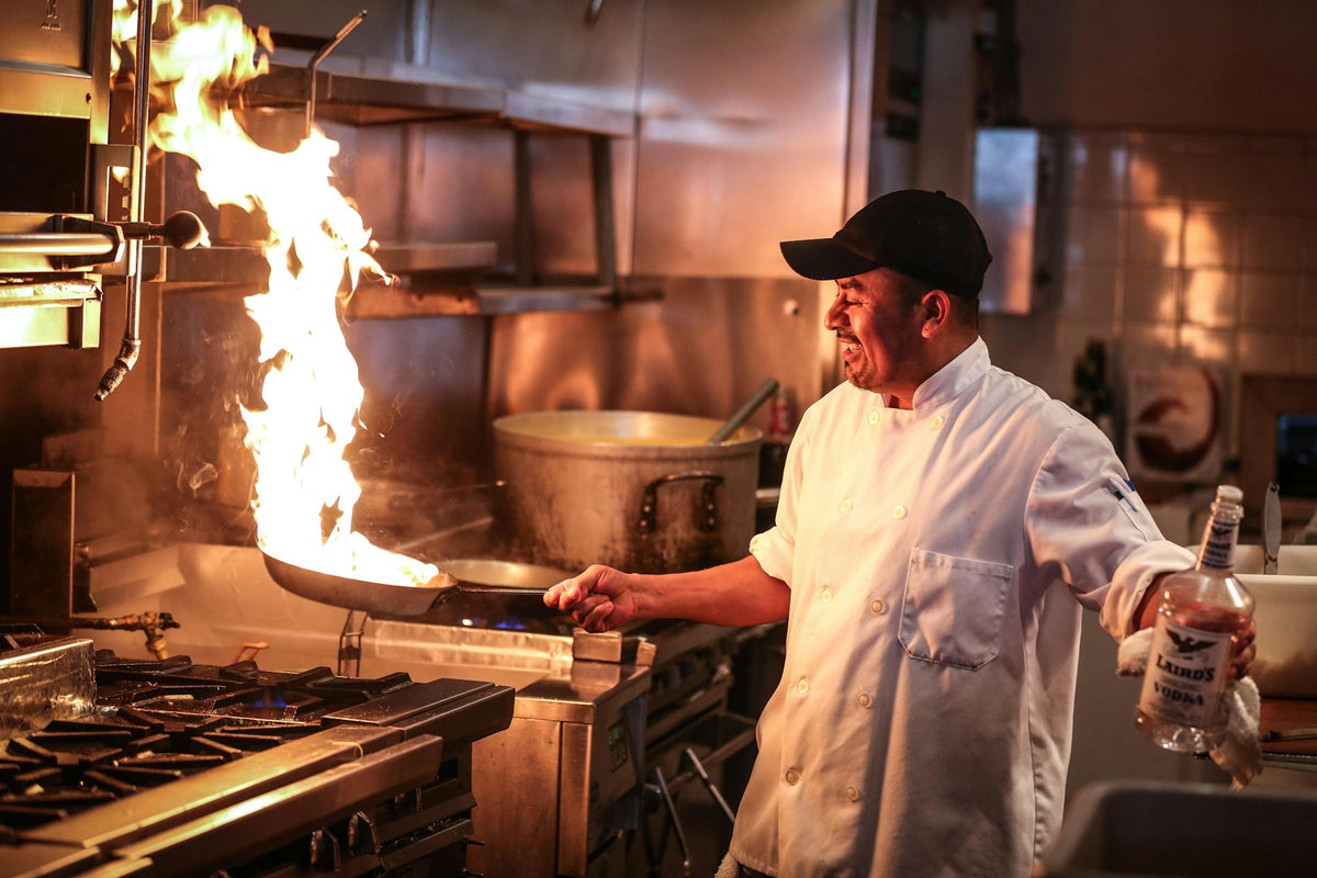 A chef cooking over a flame in a commercial kitchen